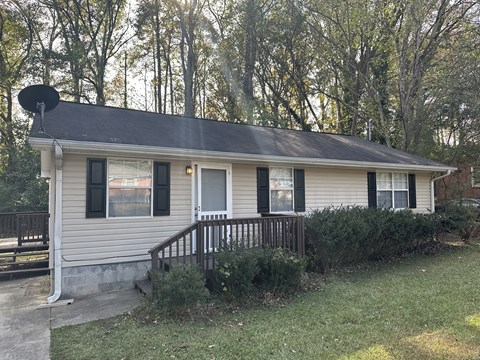 a small white house with a porch and a black roof